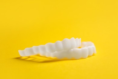 Photo of Dental mouth guards on yellow background, closeup. Bite correction