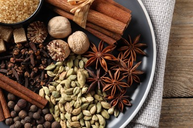 Photo of Plate with different aromatic spices on wooden table, top view