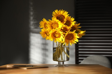 Photo of Bouquet of beautiful sunflowers on table in room