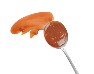 Photo of Spoon and strokes of caramel sauce isolated on white, top view