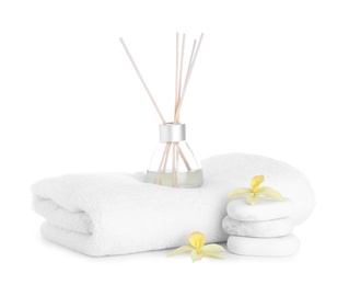 Photo of Towel, air freshener, flowers and spa stones isolated on white