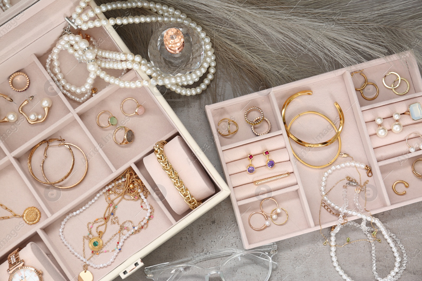 Photo of Jewelry boxes with many different accessories, glasses and perfume on light grey table, flat lay