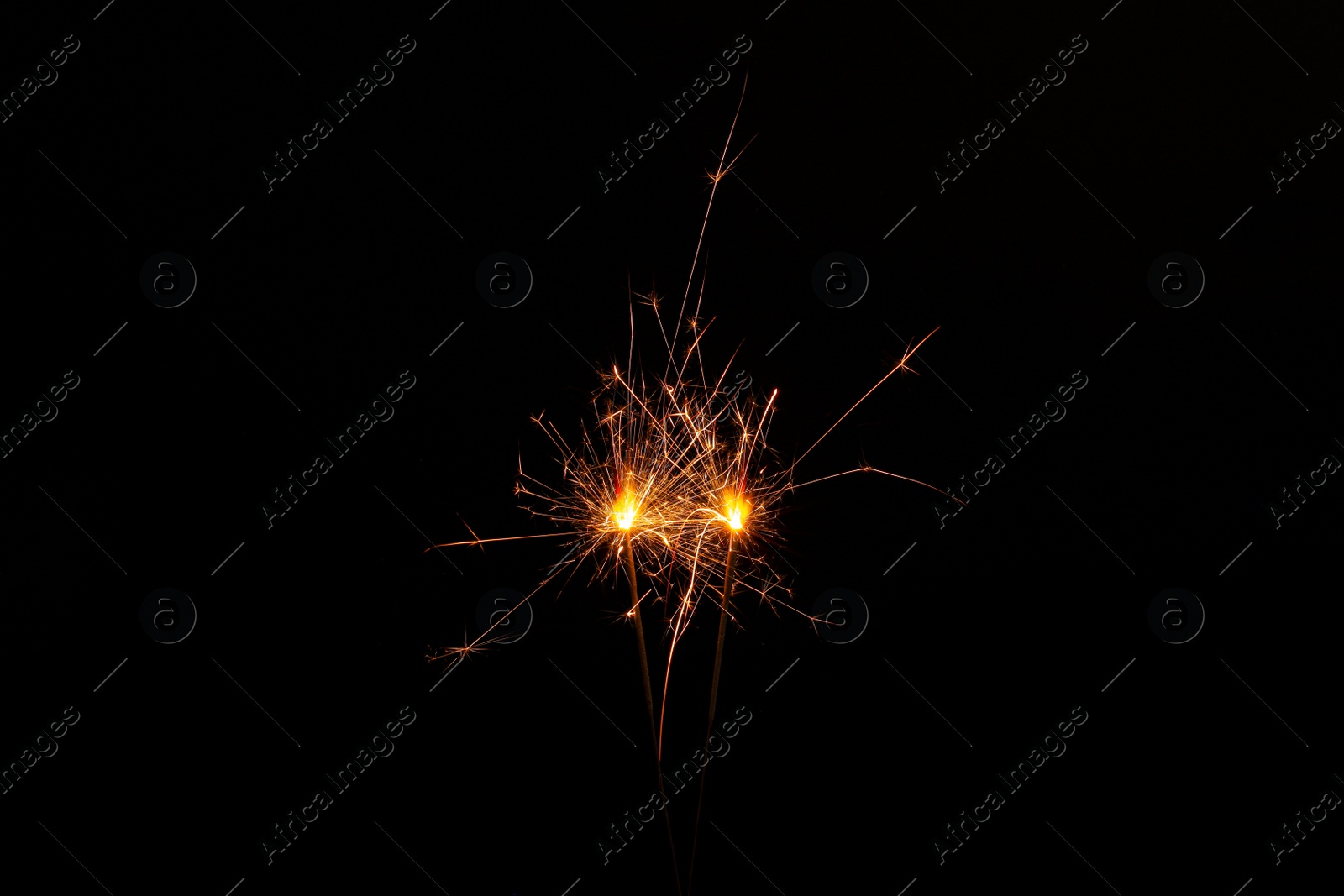 Photo of Two burning sparkler sticks on black background