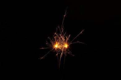 Two burning sparkler sticks on black background