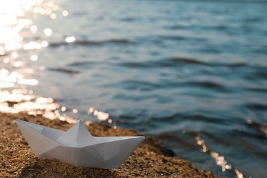 Photo of White paper boat near river on sunny day, space for text