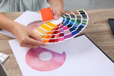 Woman with color palette samples at table, closeup