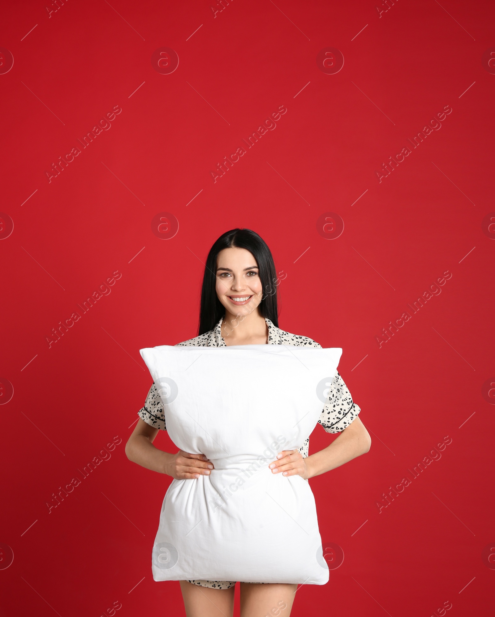 Photo of Young woman with pillow on red background