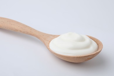 Photo of Delicious natural yogurt in spoon on light background