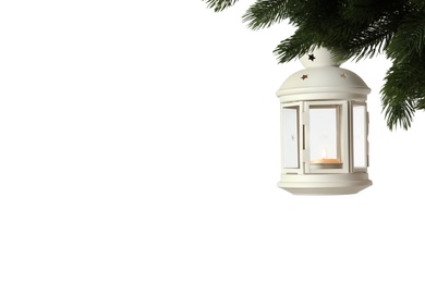 Photo of Vintage Christmas lantern with burning candle hanging on fir branch against light background. Space for text