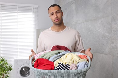 Photo of Young man with basket full of laundry in bathroom