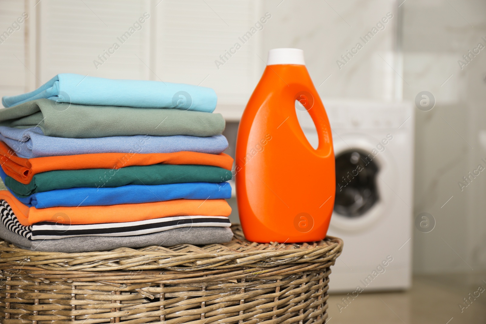 Photo of Fresh laundry and detergent on basket in bathroom