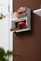 Photo of Stylish hanger for keys on brown wall in hallway