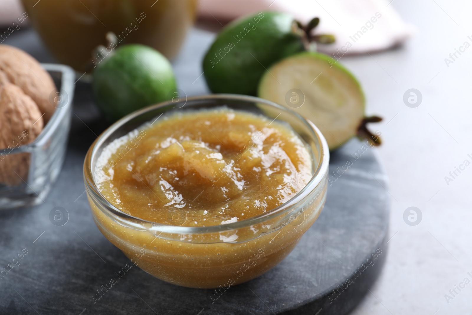 Photo of Feijoa jam in glass bowl on grey table, closeup