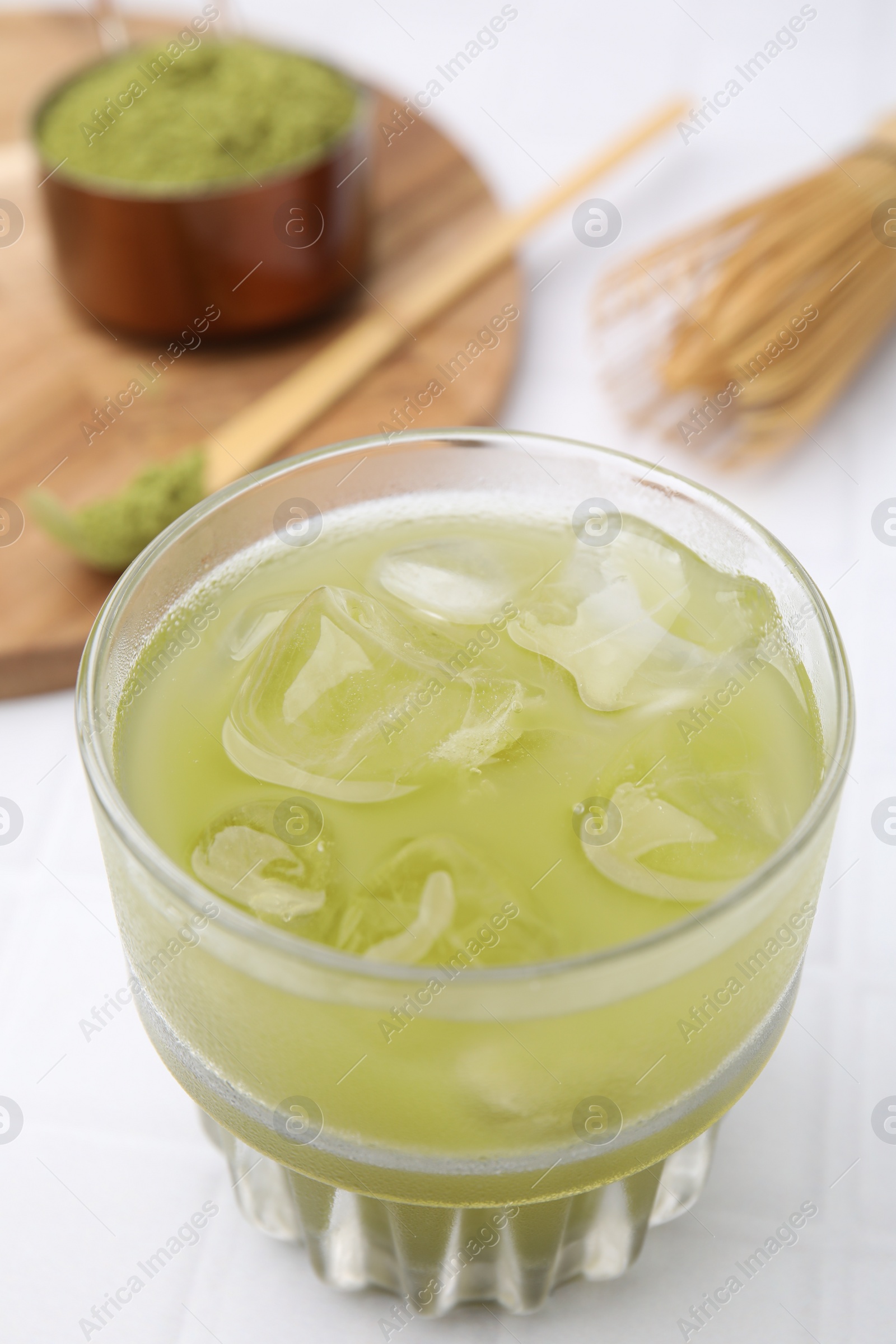 Photo of Glass of delicious iced green matcha tea on white table, closeup