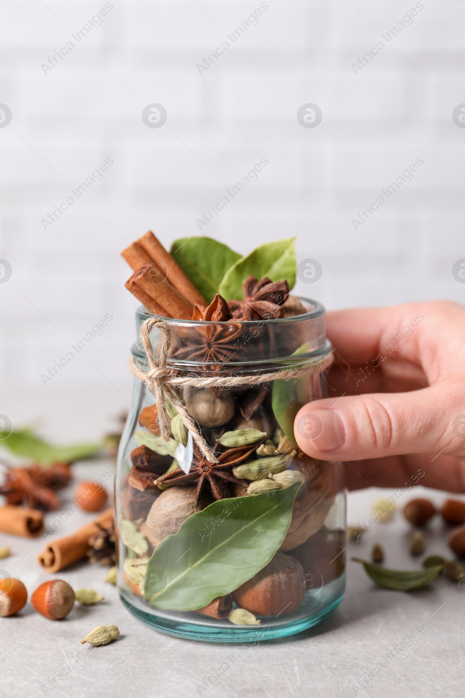 Photo of Woman holding jar with aromatic potpourri on white table, closeup