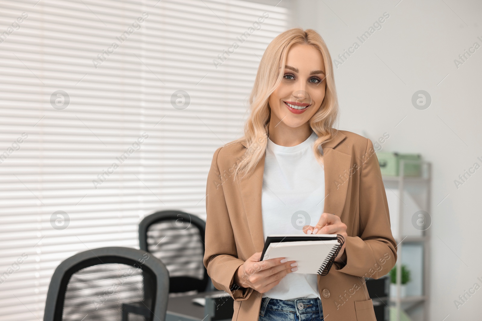 Photo of Happy secretary with notebook in office, space for text