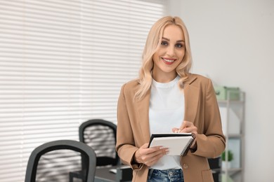 Photo of Happy secretary with notebook in office, space for text