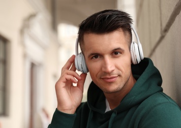 Photo of Portrait of handsome young man with headphones listening to music outdoors