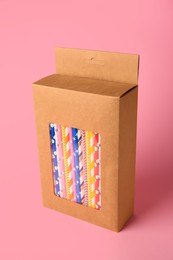 Box with many paper drinking straws on pink background