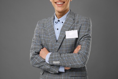 Man with blank badge on grey background, closeup