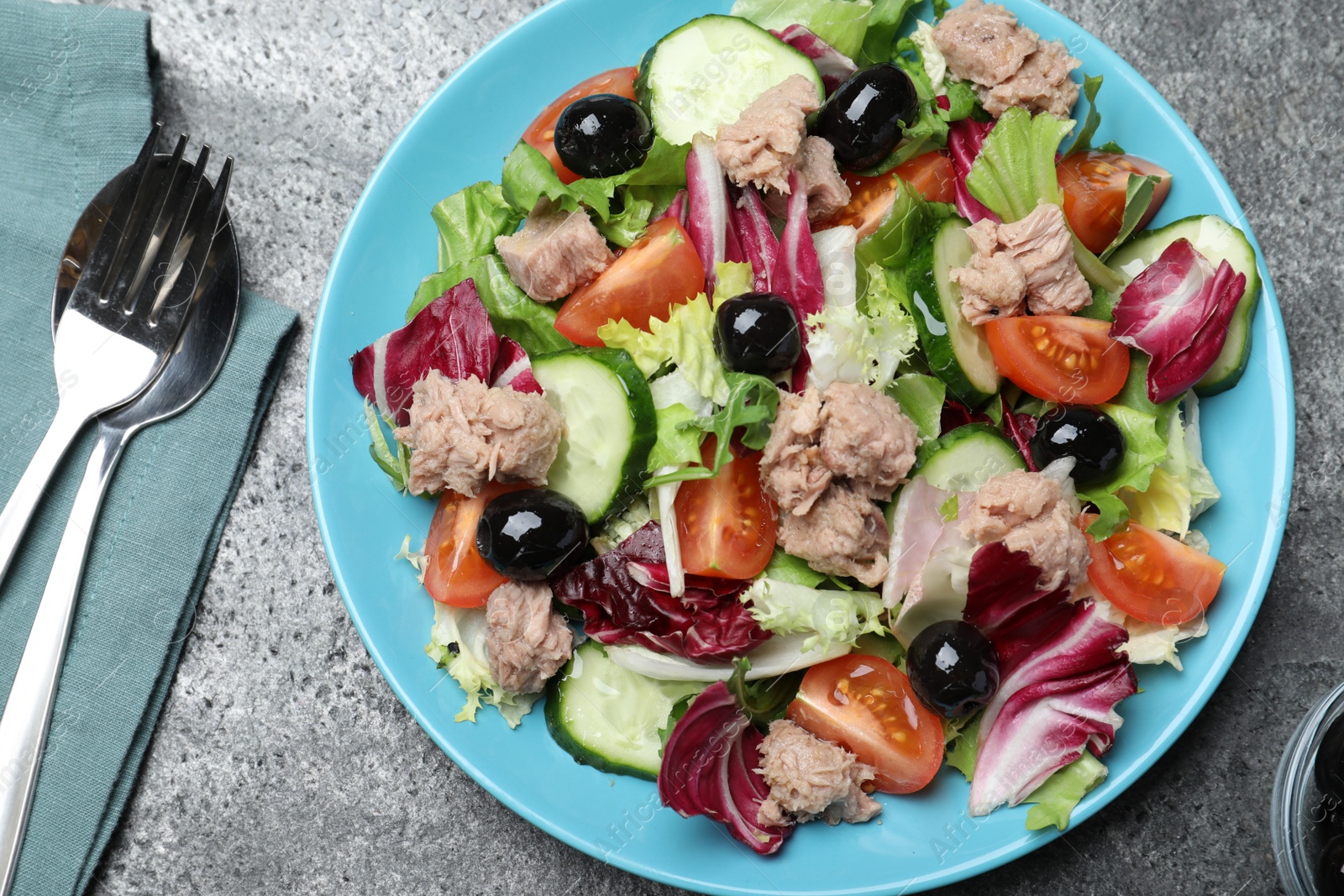 Photo of Plate of delicious salad with canned tuna and vegetables served on grey table, flat lay