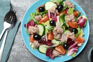 Photo of Plate of delicious salad with canned tuna and vegetables served on grey table, flat lay