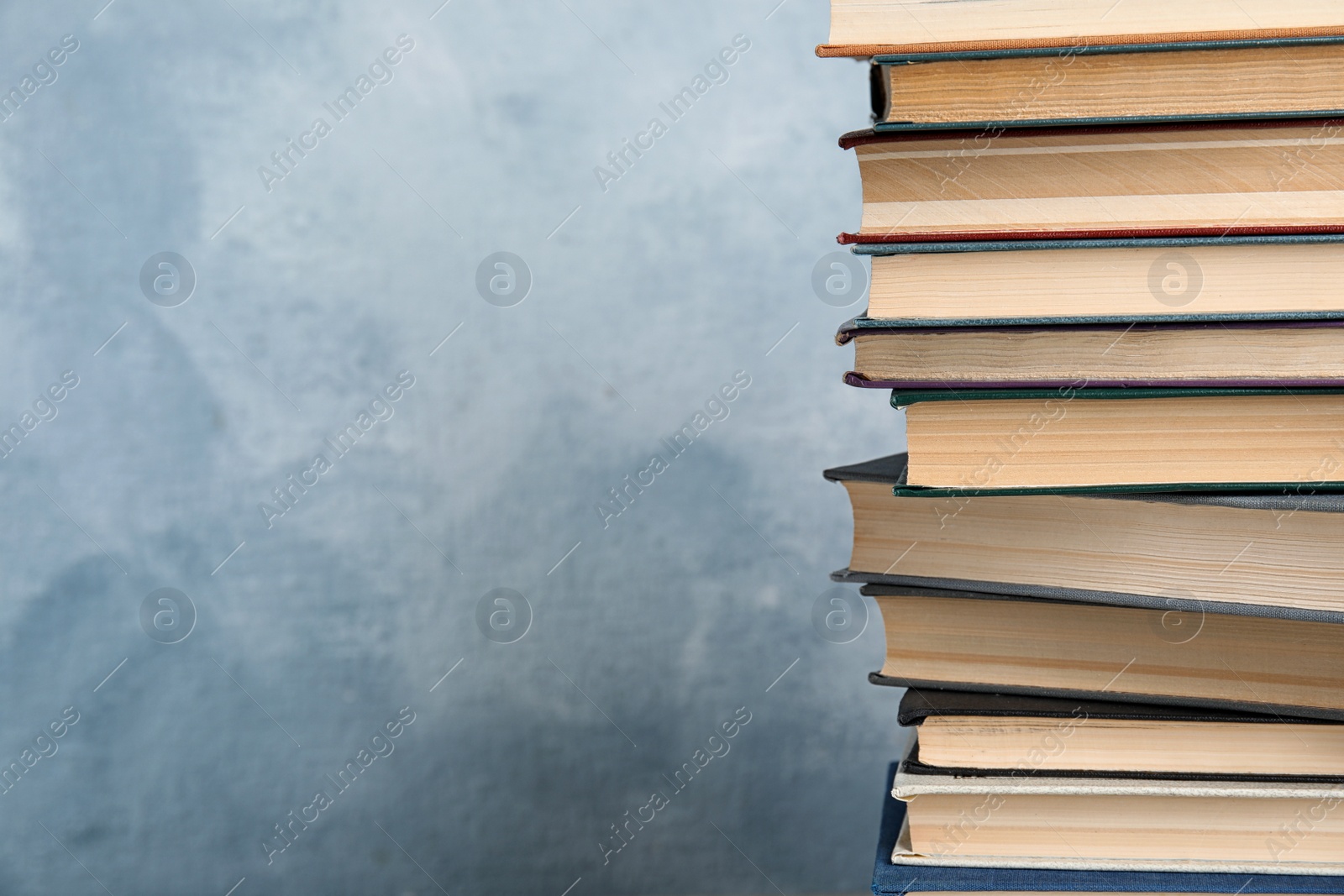 Photo of Stack of hardcover books on light blue background. Space for text