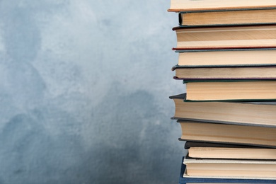 Stack of hardcover books on light blue background. Space for text