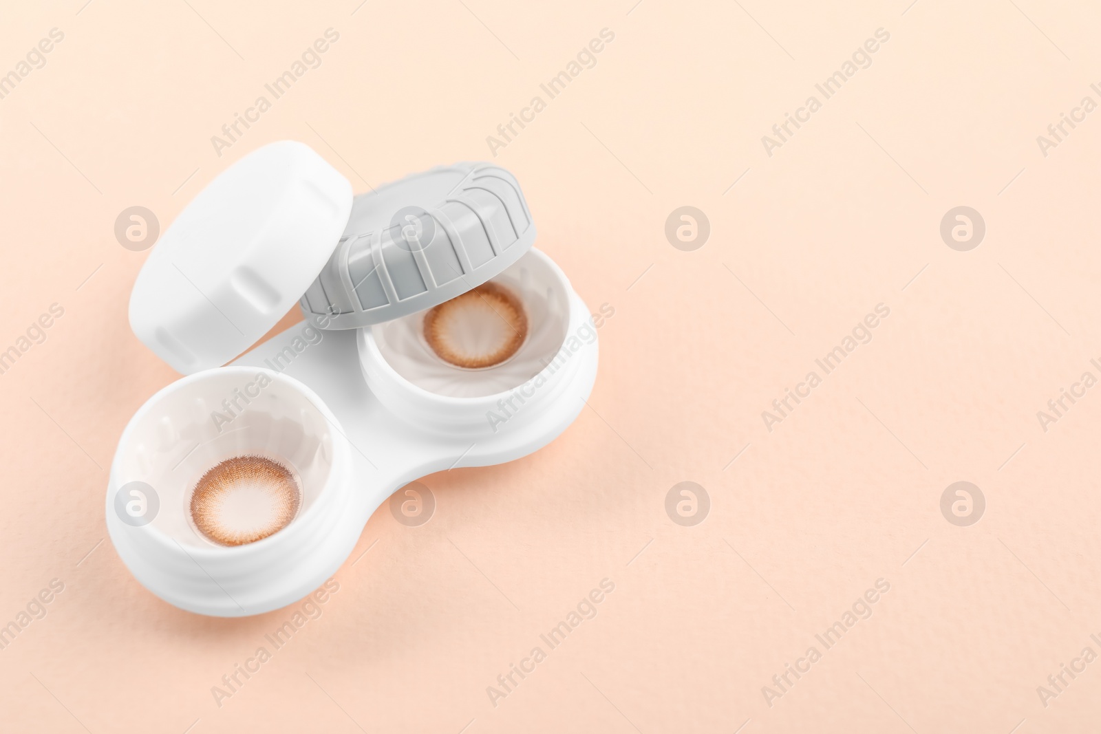 Photo of Case with color contact lenses on beige background, space for text