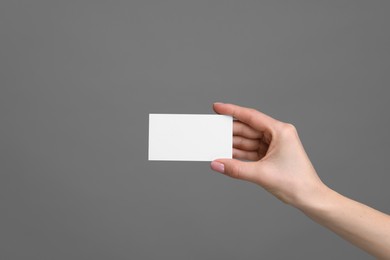 Photo of Woman holding blank business card on grey background, closeup. Space for text