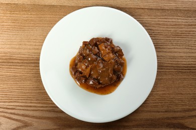 Photo of Plate with wet pet food on wooden table, top view