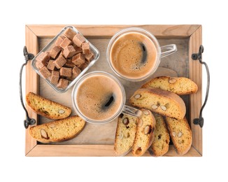 Photo of Wooden tray with tasty cantucci, cups of aromatic coffee and brown sugar on white background, top view. Traditional Italian almond biscuits