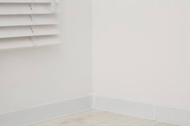 Corner of white wall with baseboard indoors