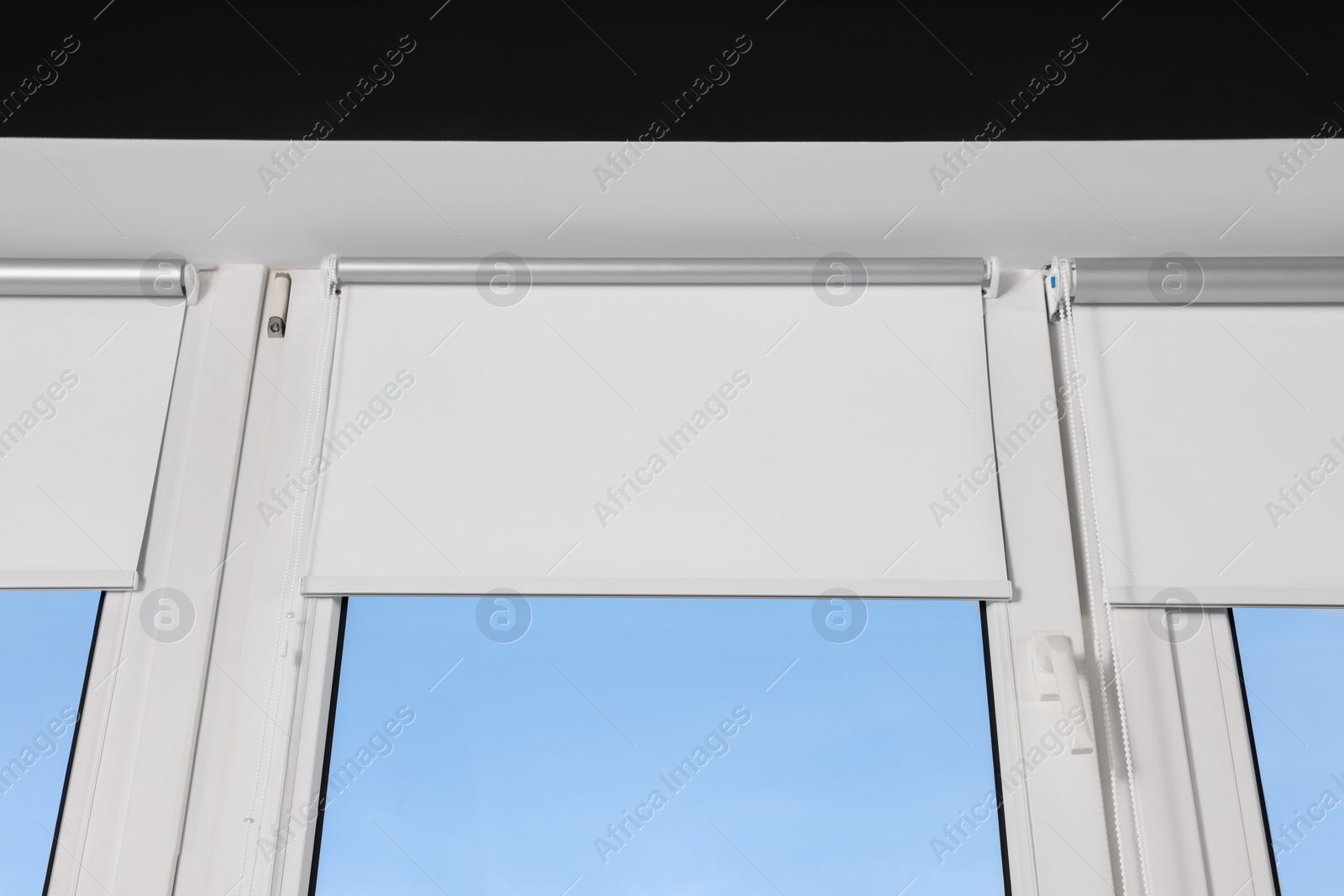 Photo of Window with open white roller blinds indoors, low angle view