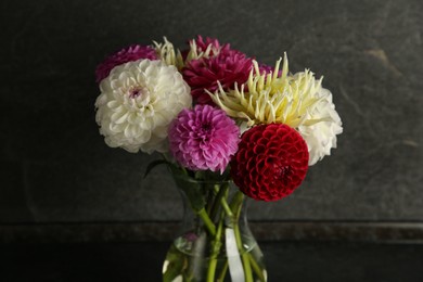 Photo of Bouquet of beautiful Dahlia flowers in vase on black table near grey wall