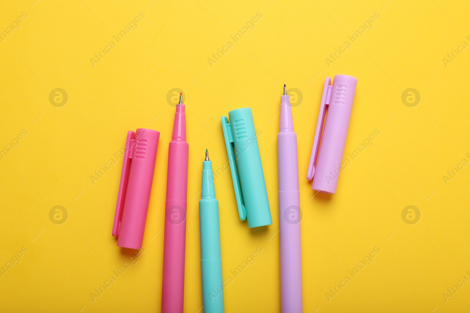 Photo of Many colorful markers on yellow background, flat lay