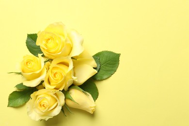 Beautiful roses on yellow background, flat lay. Space for text