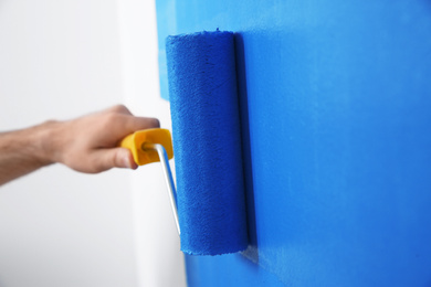 Photo of Man painting white wall with blue dye, closeup. Interior renovation