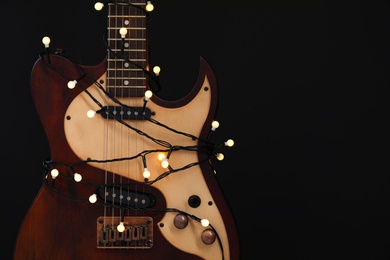 Guitar with golden lights on black background, space for text. Christmas music