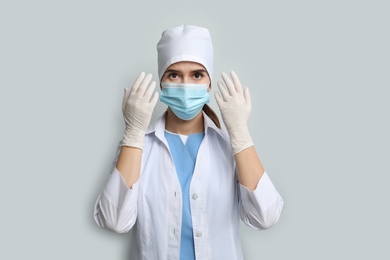 Photo of Doctor in protective mask and medical gloves against light grey background