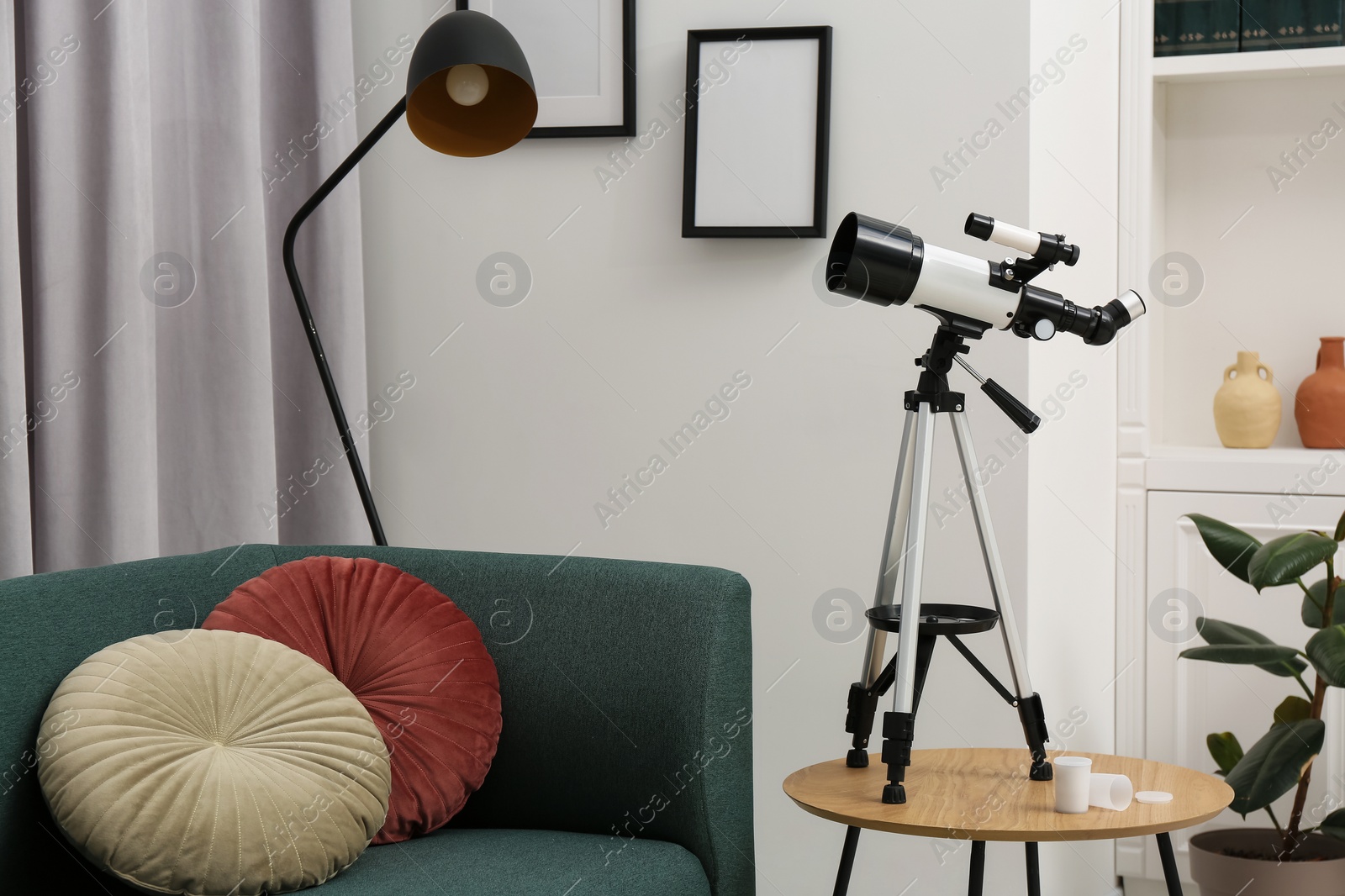 Photo of Tripod with modern telescope on table in living room