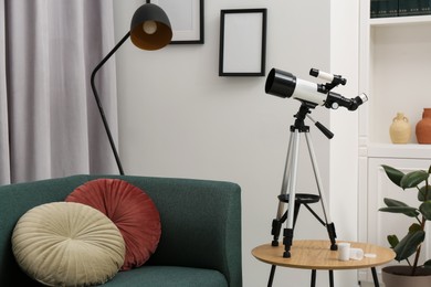 Tripod with modern telescope on table in living room