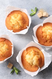 Photo of Delicious sweet muffins and brown sugar on light grey textured table, flat lay