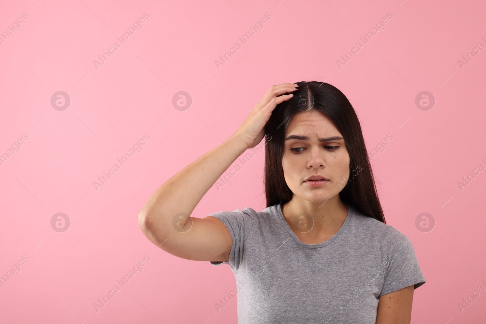 Photo of Emotional woman examining her hair and scalp on pink background, space for text