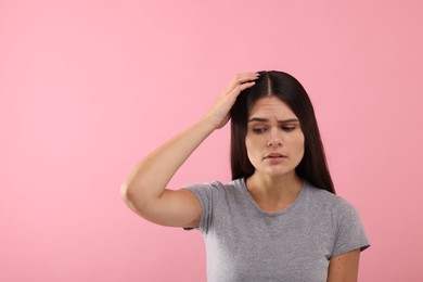 Emotional woman examining her hair and scalp on pink background, space for text