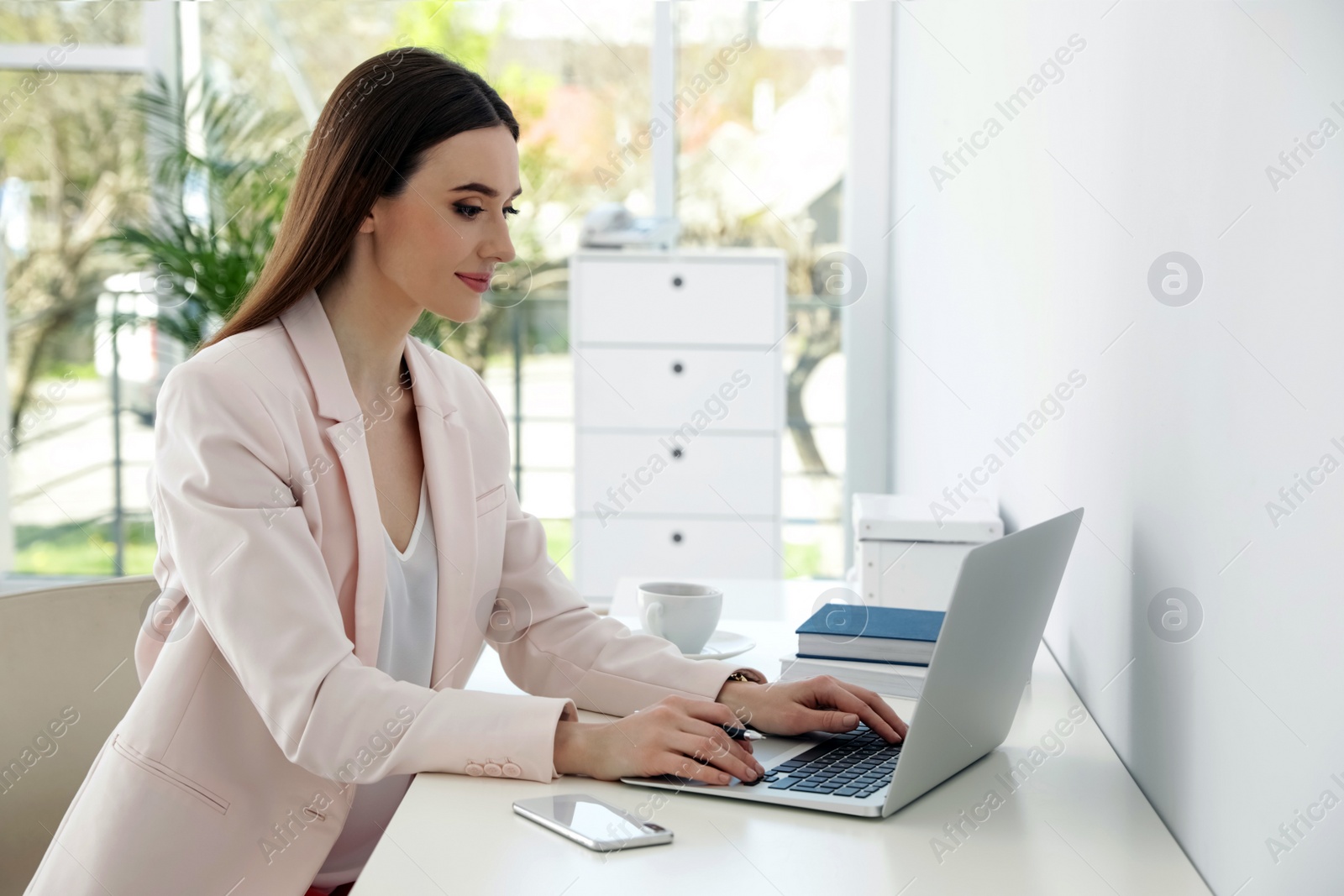 Image of Young woman working on laptop in office