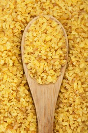 Spoon on pile of uncooked bulgur, top view