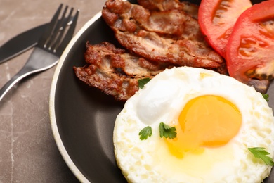 Photo of Pan with fried sunny side up egg, bacon and tomato on table, closeup