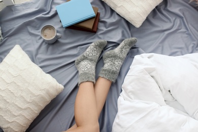 Photo of Young woman lying on bed, closeup view of legs. Winter atmosphere