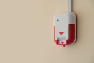 Photo of Fire alarm switch on light wall indoors. Space for text